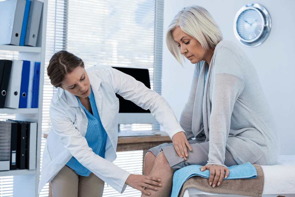Mjeku ekzaminon një pacient me artrozë të nyjës së gjurit